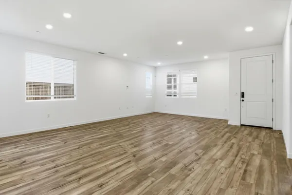 an empty room with wooden floor and windows