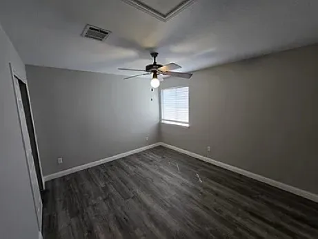 an empty room with a ceiling fan and window