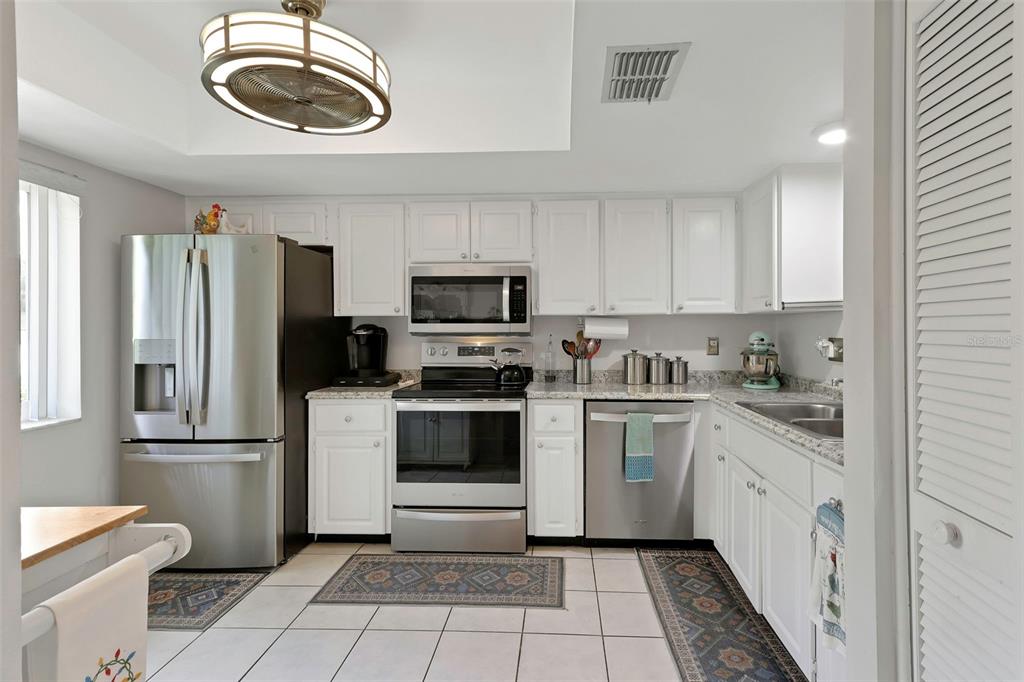 1011 Dunrobin Drive, Unit B Palm Harbor, FL 34684 - Photo 13 of 37 a kitchen with a refrigerator a stove top oven a sink dishwasher and white cabinets