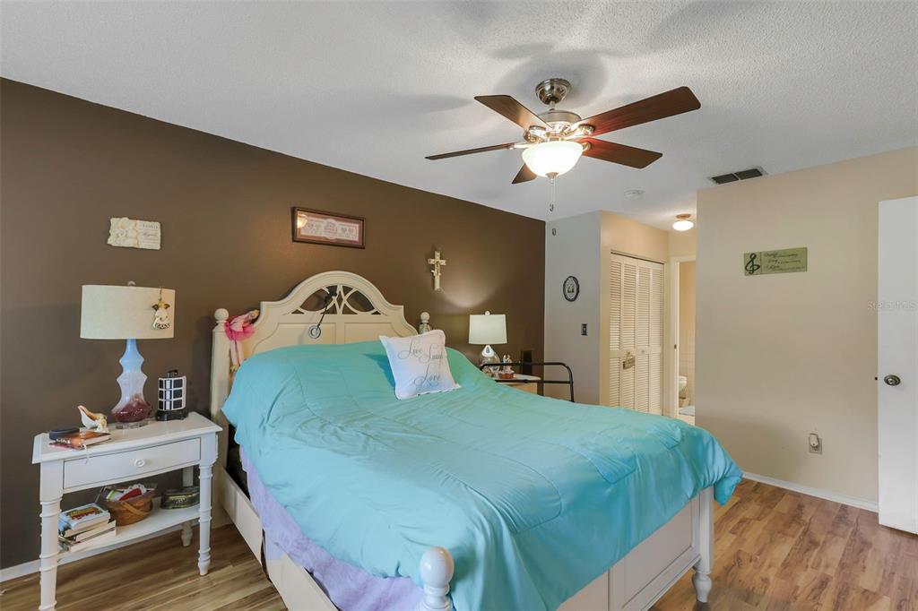1011 Dunrobin Drive, Unit B Palm Harbor, FL 34684 - Photo 18 of 37 a bedroom with a bed and a lamp on dresser with wooden floor