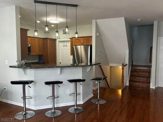 a kitchen with stainless steel appliances granite countertop a refrigerator a stove and a wooden floors