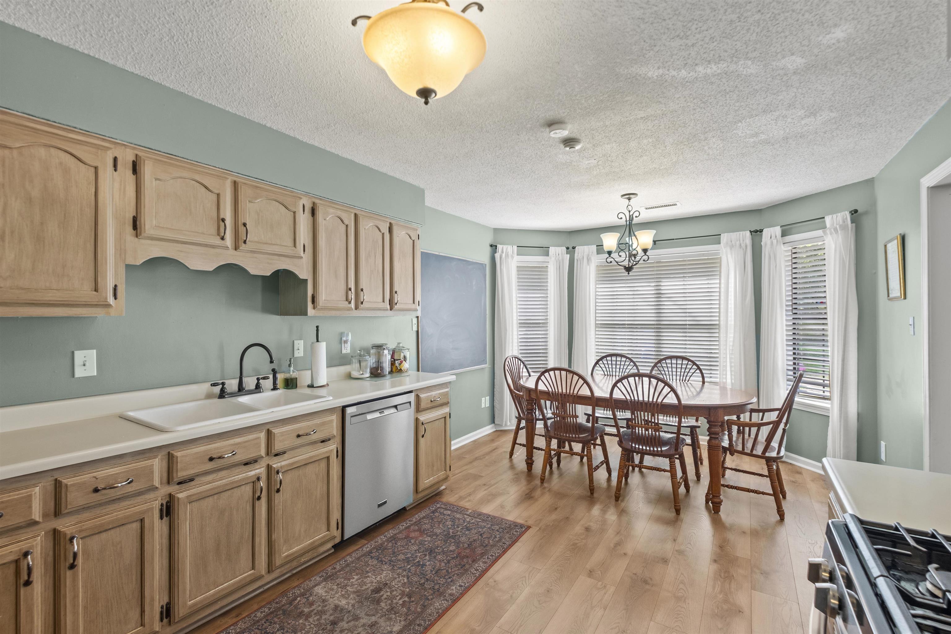 3601 Marshall Road Munford, TN 38058 - Photo 22 of 35 Kitchen and dining area featuring wood-finish flooring, light wood cabinetry with brushed nickel hardware, and a stainless steel dishwasher