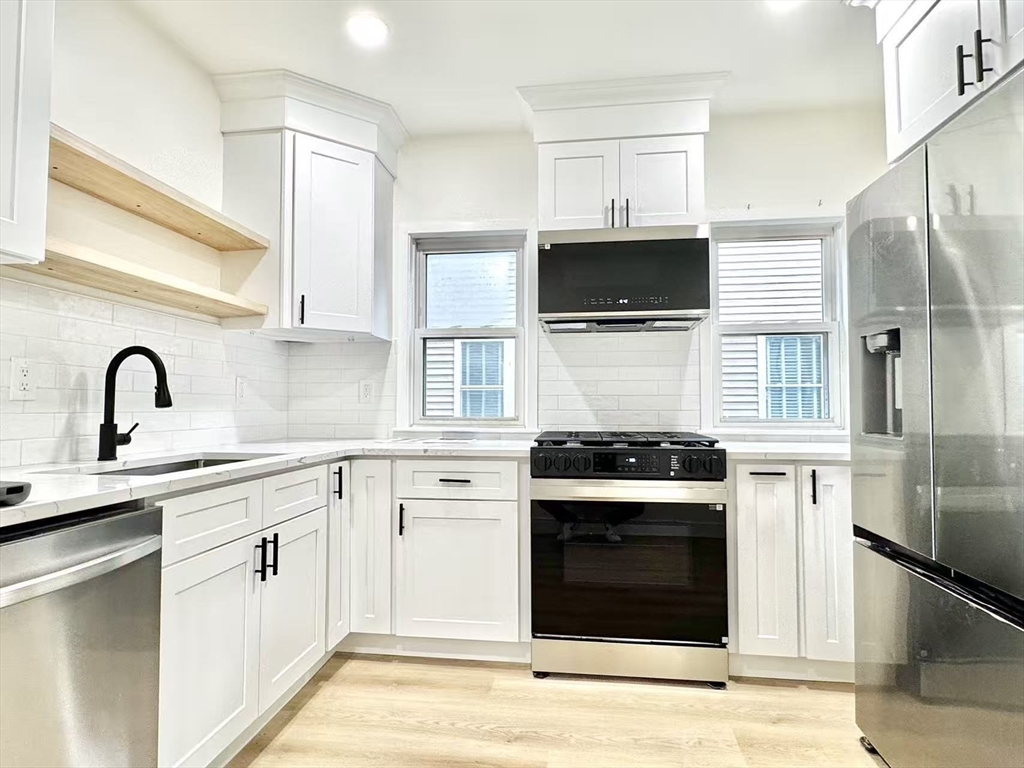 a kitchen with white cabinets and stainless steel appliances