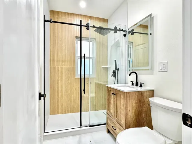 a bathroom with a shower a sink a toilet a mirror and shower
