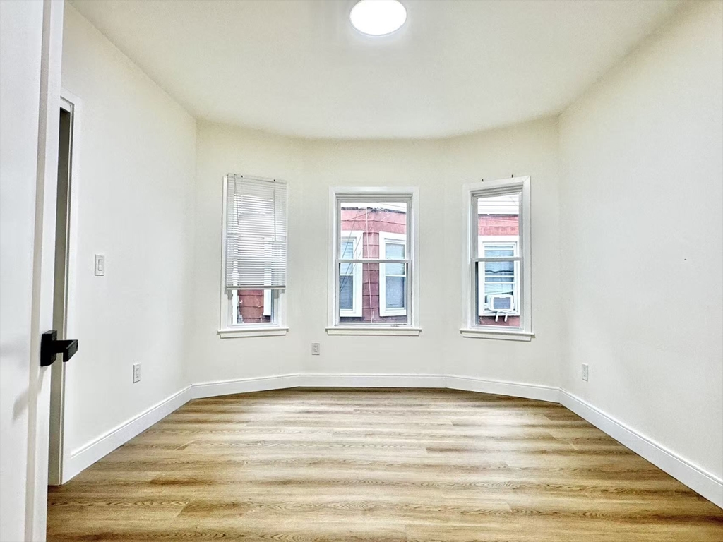 78 Orchard Street, Unit 78 Medford, MA 02155 - Photo 9 of 11 a view of an empty room with wooden floor and a window