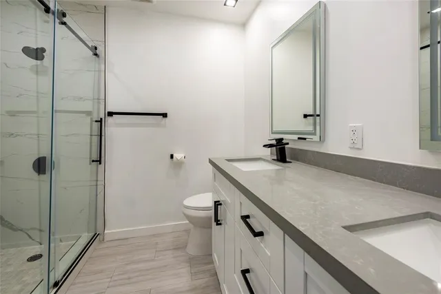 a bathroom with a granite countertop sink a toilet and shower