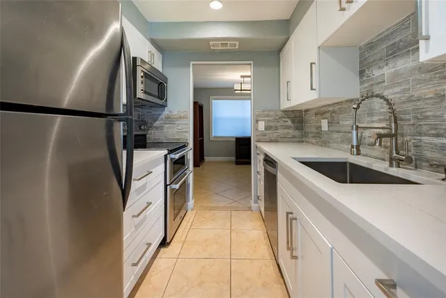 a kitchen with stainless steel appliances granite countertop a sink and a refrigerator