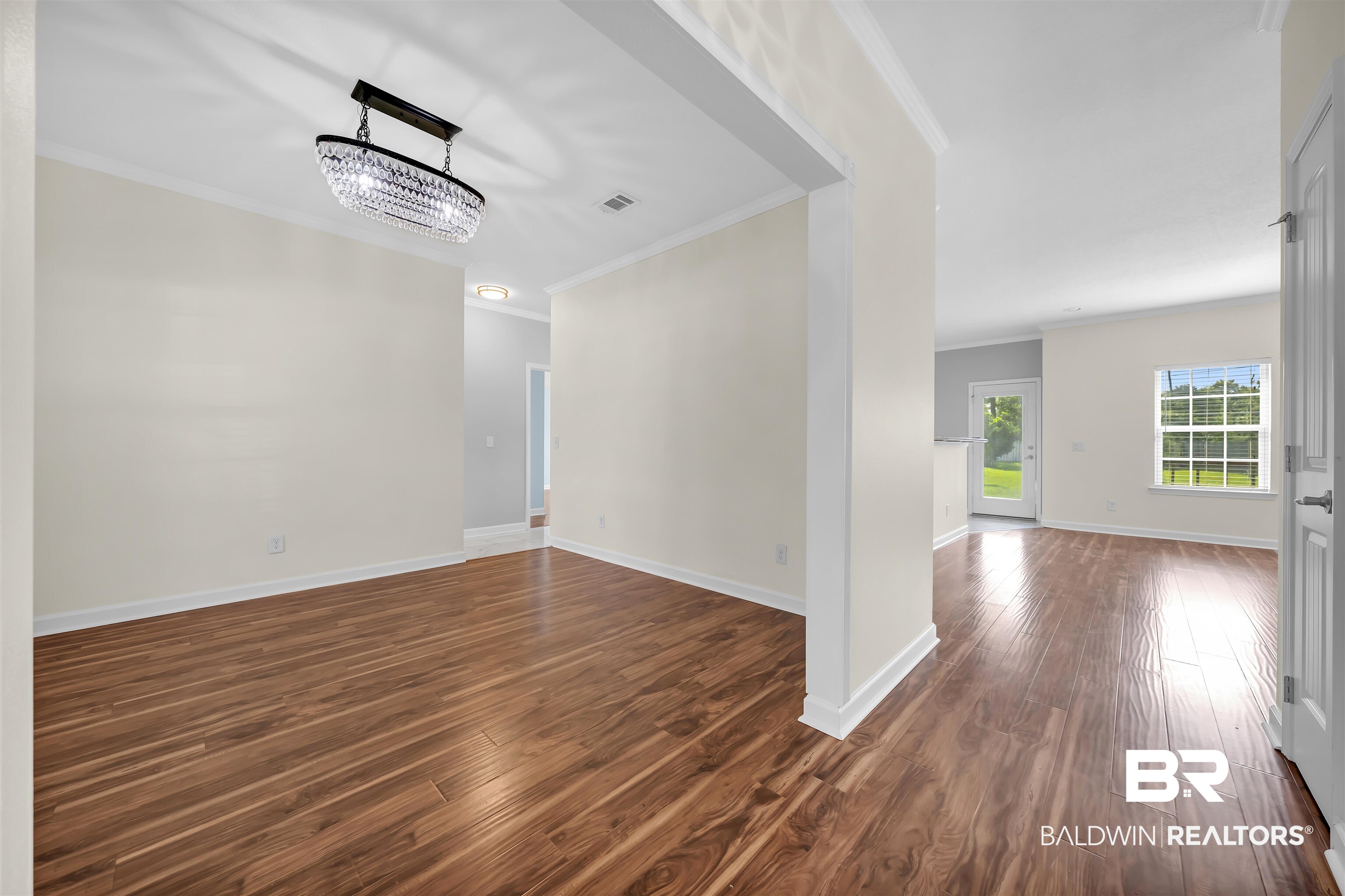 10147 Lyttleton Loop Lillian, AL 36549 - Photo 9 of 29 Expansive room featuring wood-finish flooring, a contemporary crystal chandelier, and white baseboards