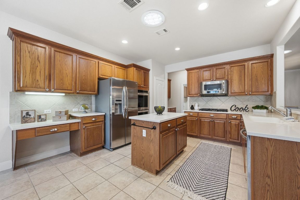512 Armstrong Drive Georgetown, TX 78633 - Photo 15 of 40 a kitchen with stainless steel appliances granite countertop a stove top oven a sink dishwasher and a refrigerator with wooden cabinets