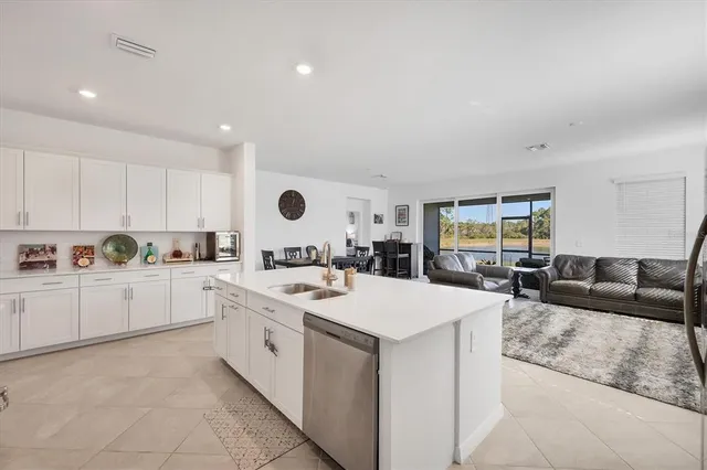 a kitchen with stainless steel appliances granite countertop a stove a sink a refrigerator and white cabinets with wooden floor