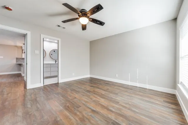 an empty room with wooden floor and ceiling fan