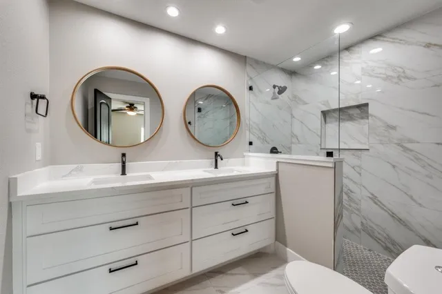 a bathroom with a toilet a double vanity sink and a mirror