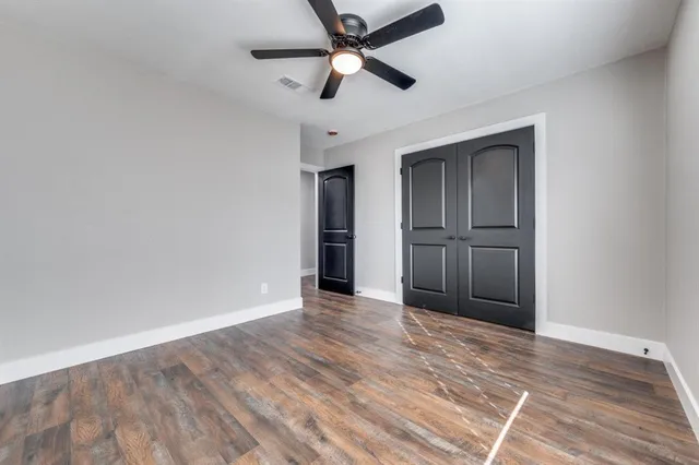 a view of empty room with wooden floor and ceiling fan