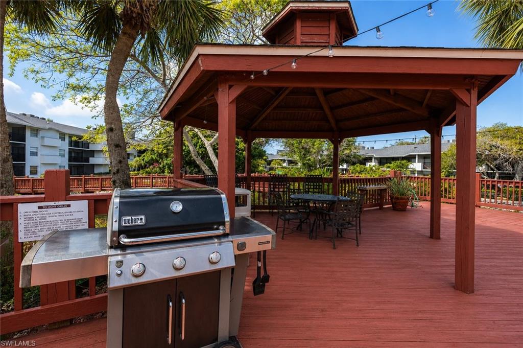 600 Neapolitan Way, Unit 449 Naples, FL 34103 - Photo 33 of 44 Expansive outdoor deck featuring a red-stained finish, a built-in gazebo structure, and perimeter railing