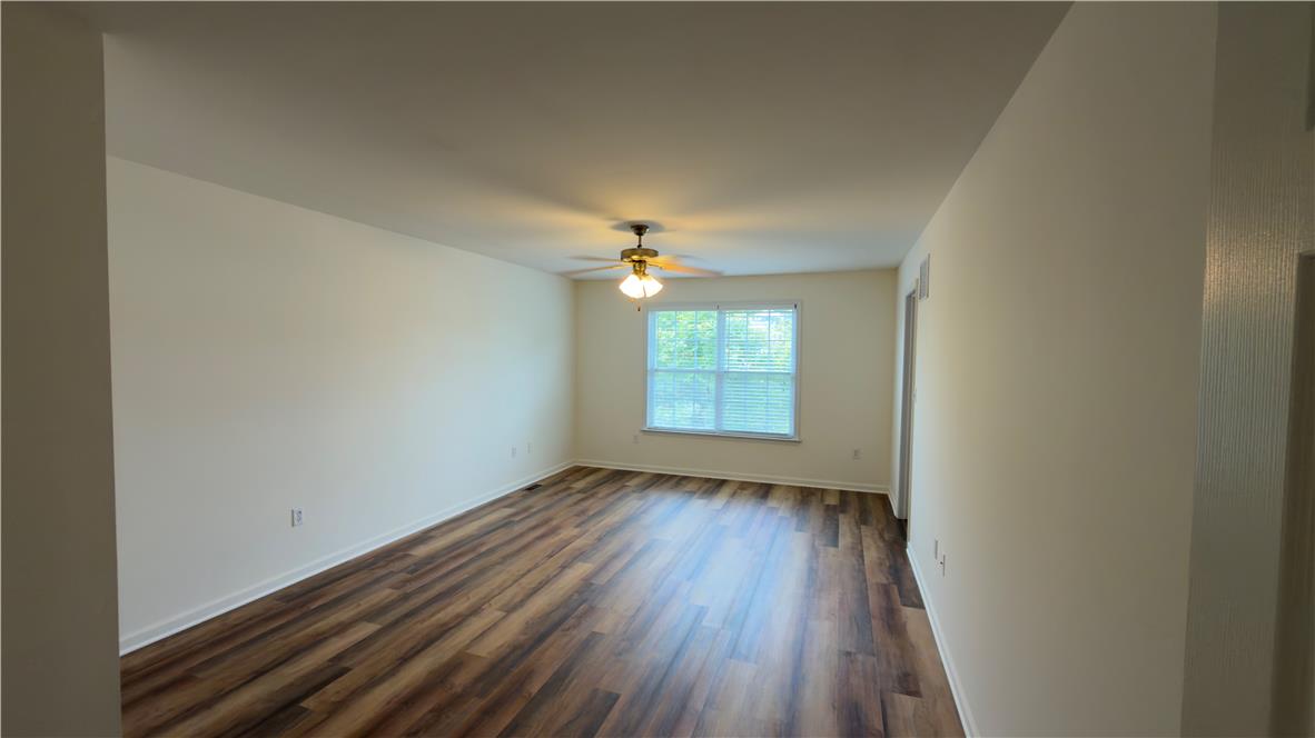 4172 Ross Road Bethlehem, PA 18020 - Photo 13 of 16 Rich wood-look flooring stretches across a spacious living area illuminated by natural light.