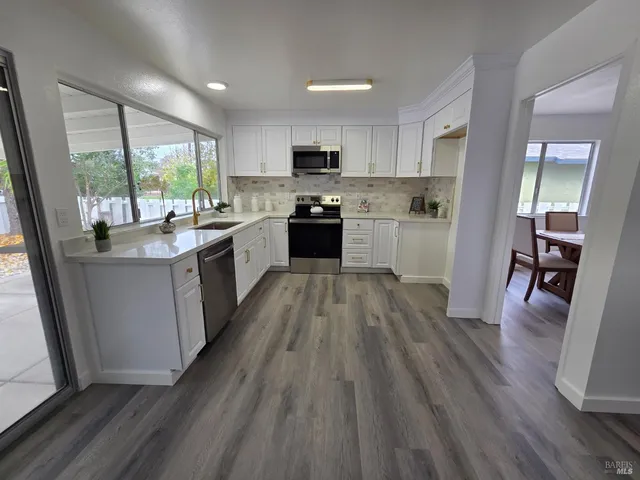 a large kitchen with a center island wooden floor stainless steel appliances and windows