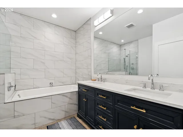 a bathroom with a double vanity sink mirror and bathtub