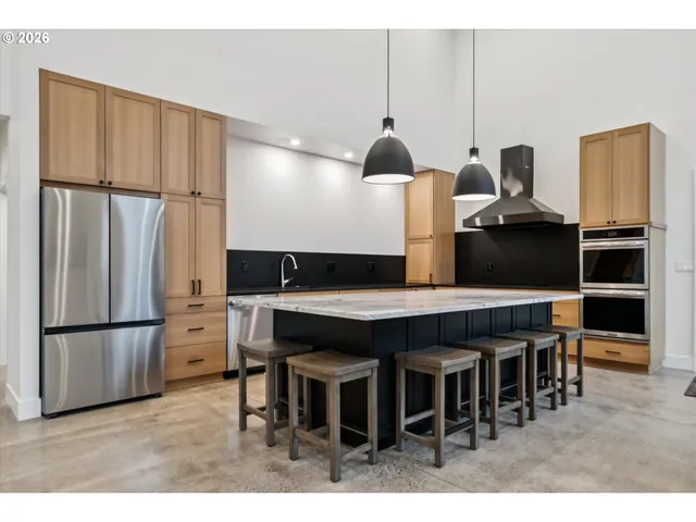 a kitchen with stainless steel appliances kitchen island granite countertop a table chairs and a refrigerator