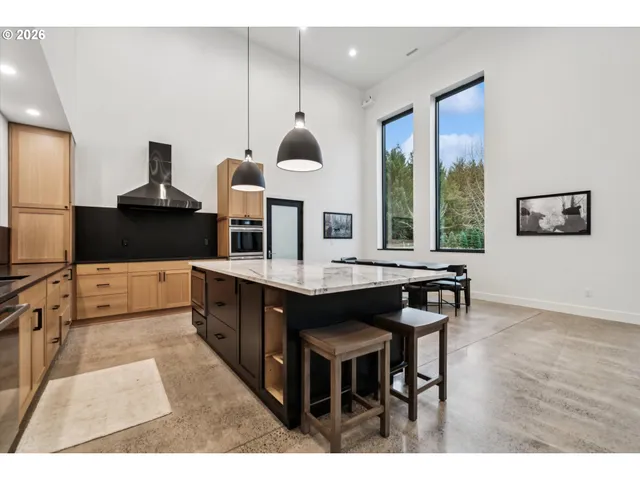 a kitchen with stainless steel appliances kitchen island granite countertop a table chairs in it and wooden floors