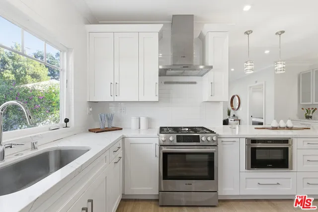 a kitchen with stainless steel appliances granite countertop a sink a stove a refrigerator and island with wooden floor