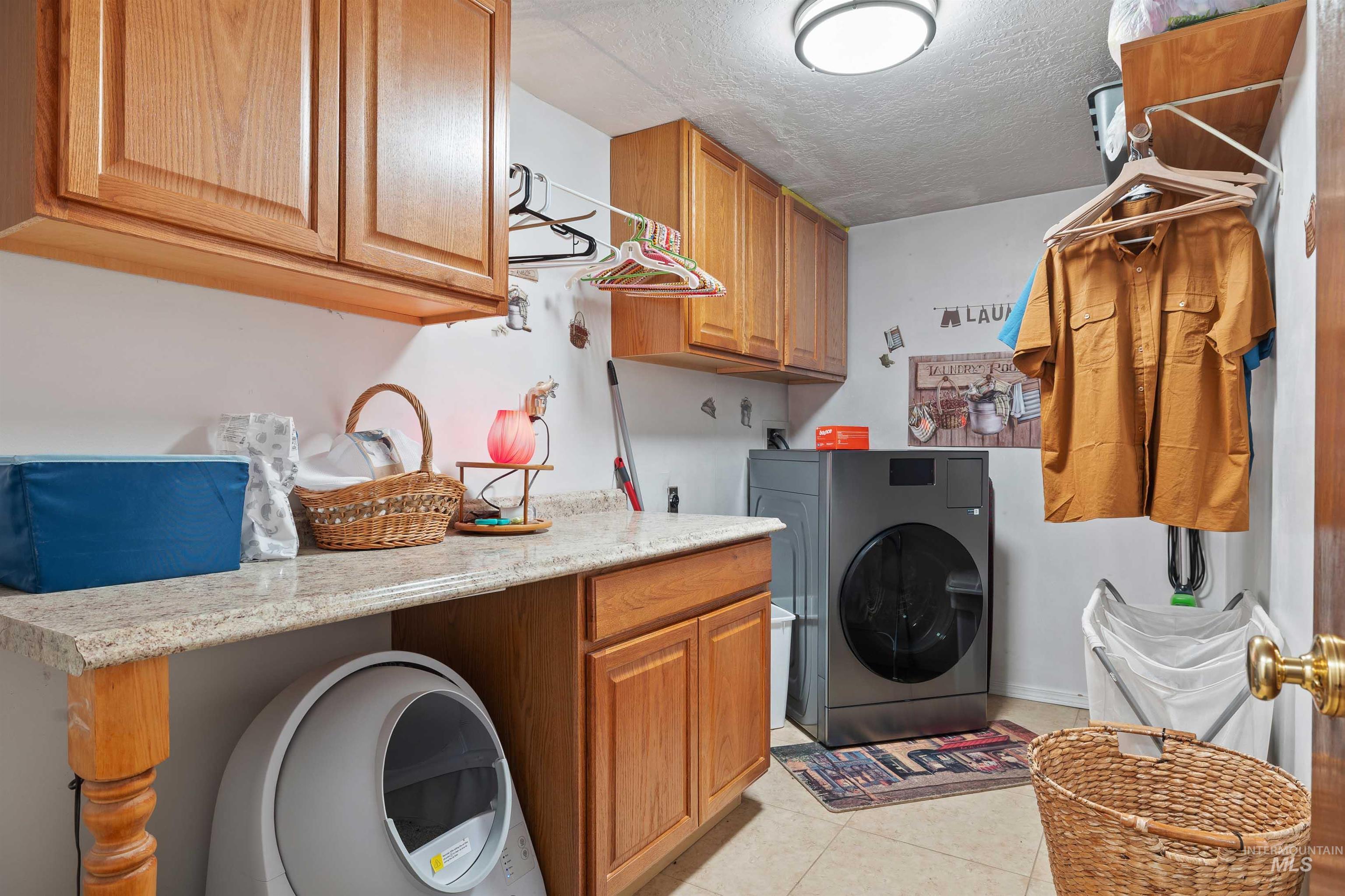 216 Ranch View Road West Jerome, ID 83338 - Photo 25 of 42 Laundry room featuring wood cabinetry, stone-finish countertops, ceramic tile flooring, and a flush-mount ceiling light