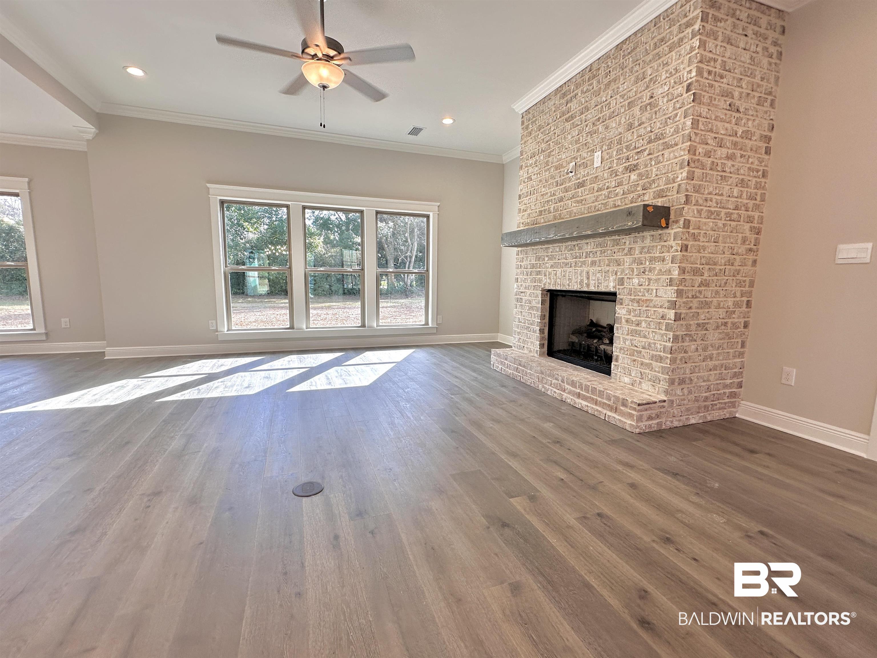 630 Kitfox Avenue Fairhope, AL 36532 - Photo 5 of 40 Unfurnished living room with a brick fireplace, crown molding, and hardwood / wood-style floors