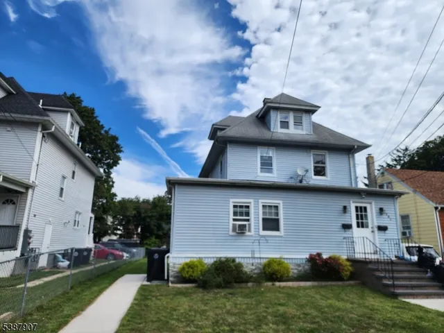 a view of a house with a yard plants and large tree