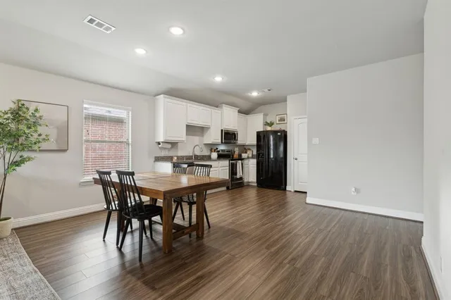 an open kitchen with wooden floor and stainless steel appliances