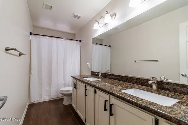 a bathroom with a granite countertop sink a toilet and a mirror