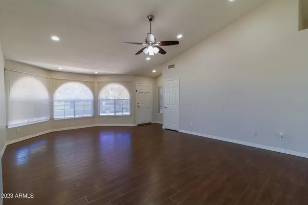 an empty room with wooden floor chandelier fan and window
