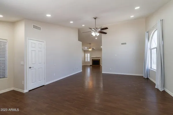 an empty room with wooden floor and a ceiling fan