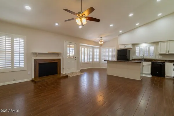 a view of an empty room with wooden floor and a kitchen