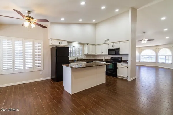 a kitchen with stainless steel appliances kitchen island granite countertop a stove a refrigerator a sink and a microwave with wooden floor