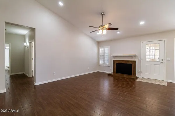an empty room with wooden floor fireplace and windows