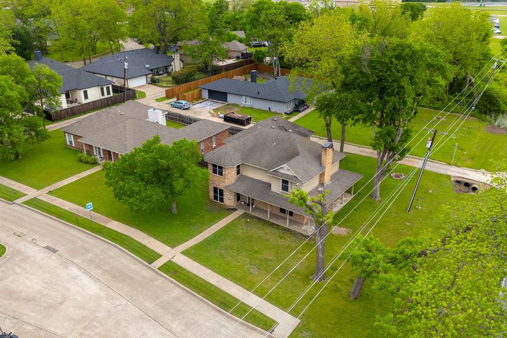 104 Pecan Grove Lancaster, TX 75146 - Photo 11 of 33 Aerial view of the property featuring a two-story residence with a covered front porch, a brick chimney, and a well-maintained lawn with mature trees