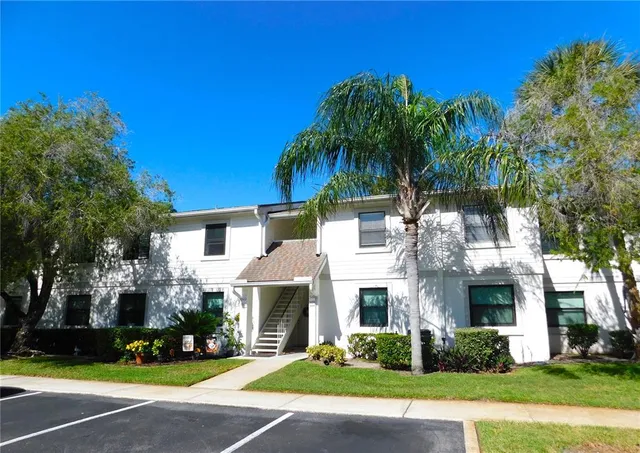 a front view of a house with garden and trees