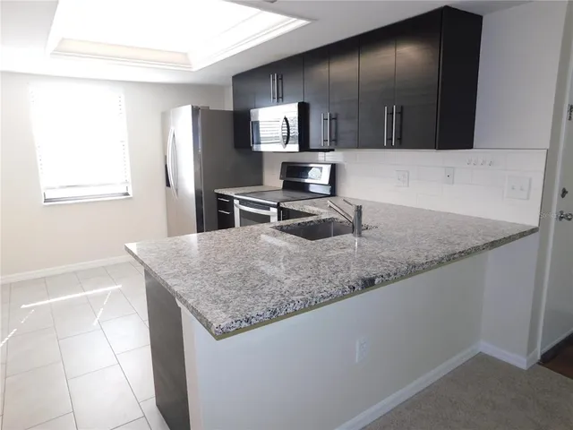 a kitchen with granite countertop stainless steel appliances a sink stove and refrigerator