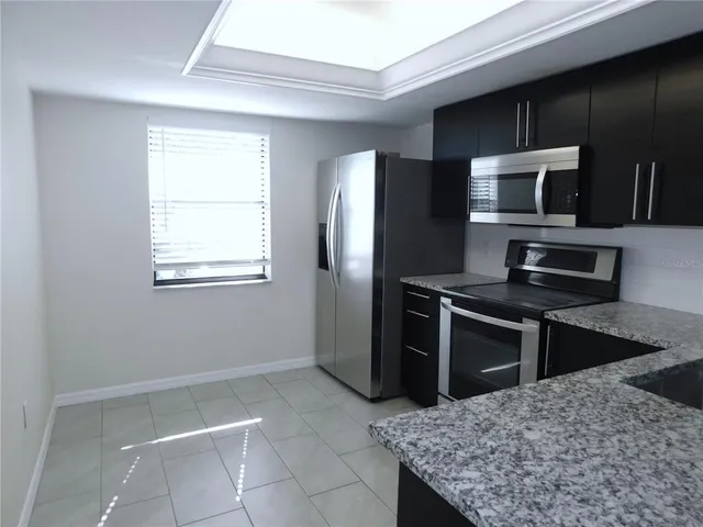 a kitchen with stainless steel appliances kitchen island granite countertop a refrigerator and a stove top oven