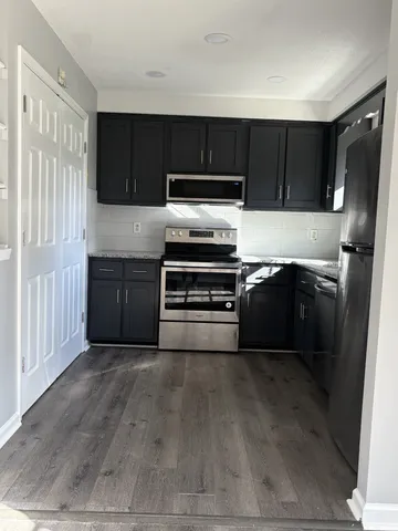 a kitchen with granite countertop a refrigerator and a stove top oven