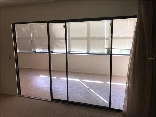 a view of an empty room with wooden floor and windows