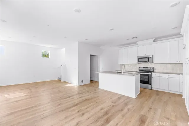a kitchen with granite countertop a refrigerator and white cabinets