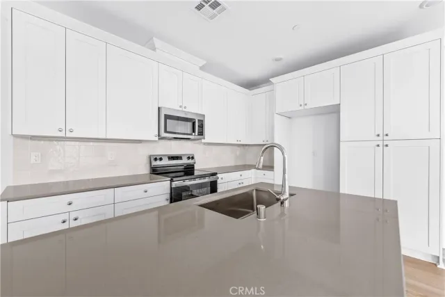 a kitchen with granite countertop white cabinets and stainless steel appliances