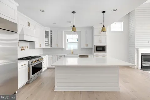 a kitchen with kitchen island a stove a sink a chimney wooden floor and cabinets