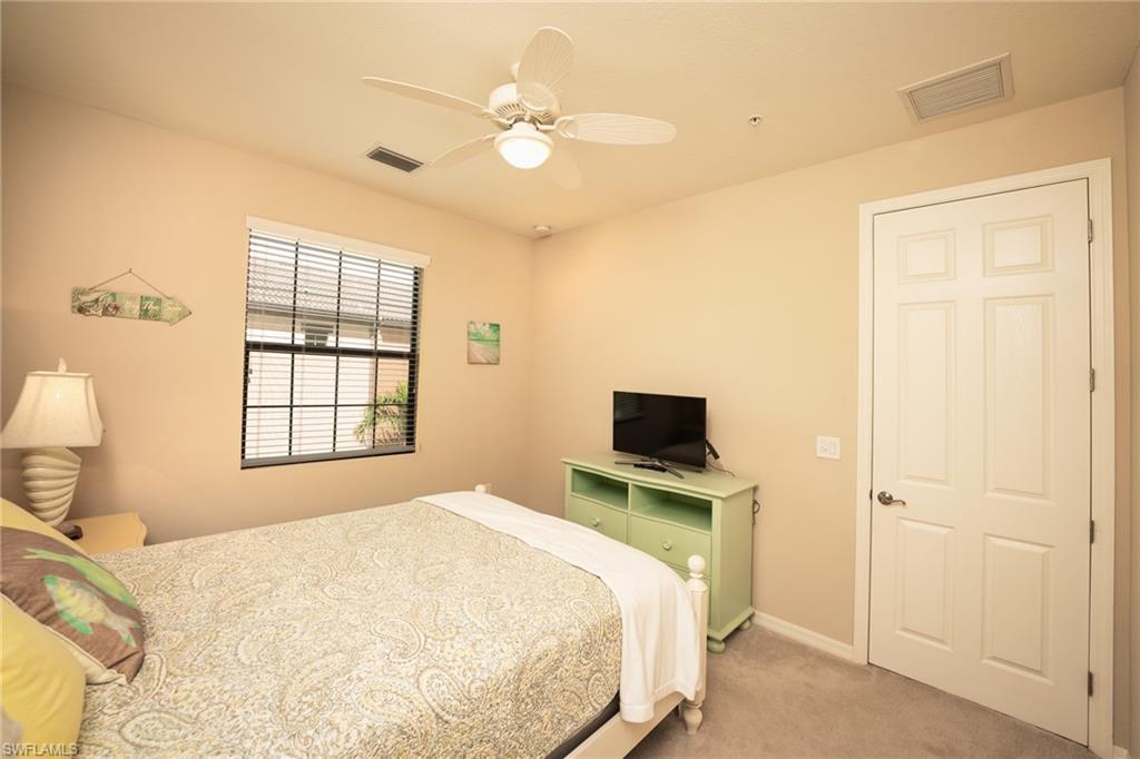 9054 Capistrano Street North, Unit 4002 Naples, FL 34113 - Photo 14 of 26 a bedroom with a bed a window and a flat screen tv