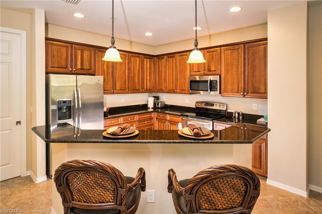 9054 Capistrano Street North, Unit 4002 Naples, FL 34113 - Photo 4 of 26 a kitchen with kitchen island a stove a sink and a refrigerator with wooden floor