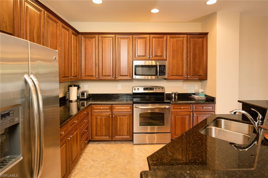 9054 Capistrano Street North, Unit 4002 Naples, FL 34113 - Photo 5 of 26 a kitchen with stainless steel appliances granite countertop a refrigerator a stove top oven a sink and dishwasher
