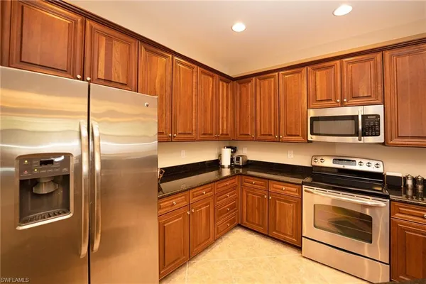 a kitchen with stainless steel appliances granite countertop a refrigerator a stove top oven a sink and dishwasher