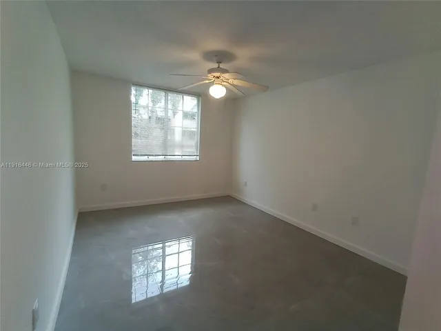 an empty room with a window and a fan