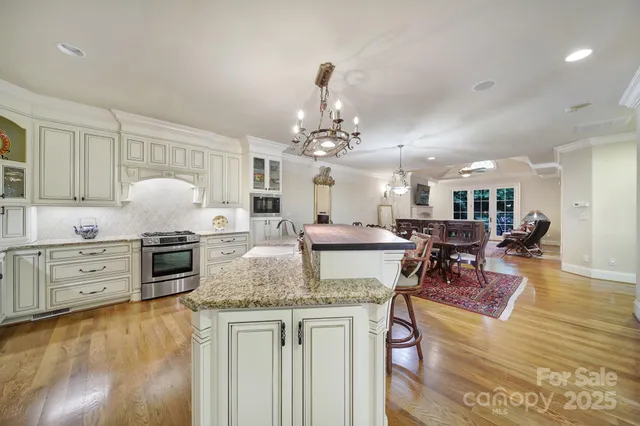 a large white kitchen with lots of counter space and chandelier