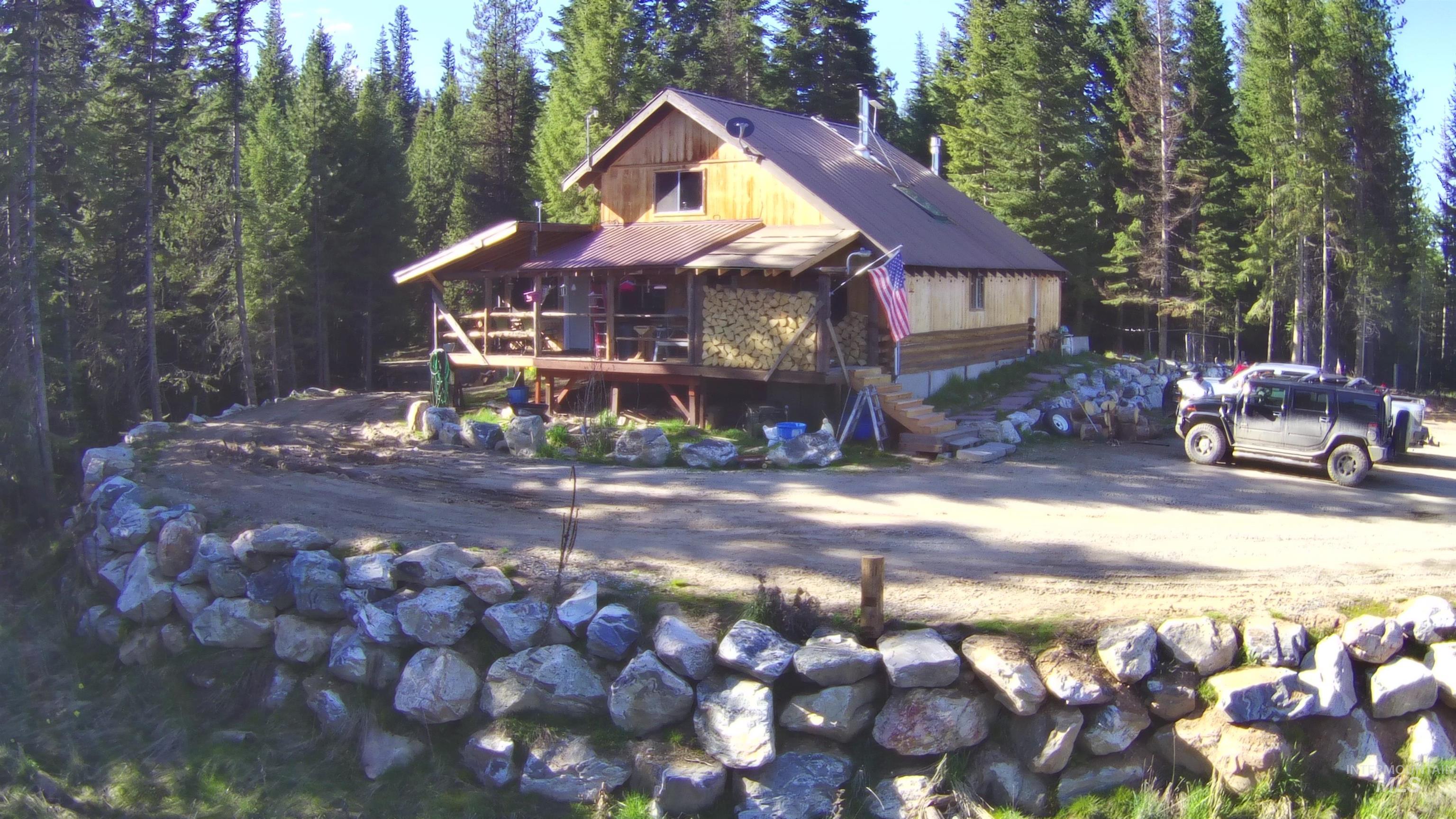 Wood-sided cabin featuring a covered porch, stone retaining walls, and a metal roof